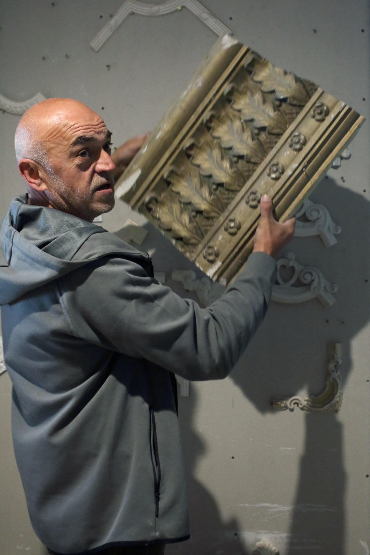 Master fitting a long acanthus frieze to a wall