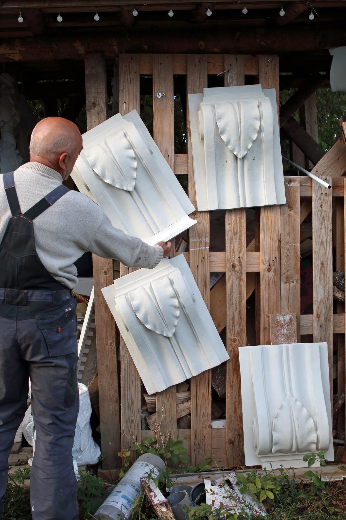 Master arranges freshly cast plaster panels in the workshop yard